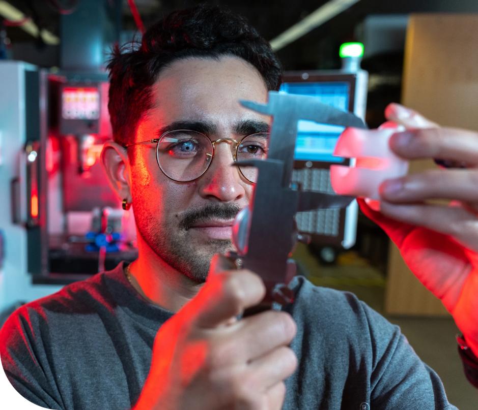 A focusedDU student using precision measurement tools in a laboratory setting, with red and blue lighting highlighting the equipment.