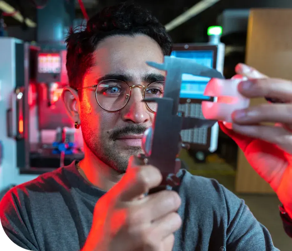 A focusedDU student using precision measurement tools in a laboratory setting, with red and blue lighting highlighting the equipment.